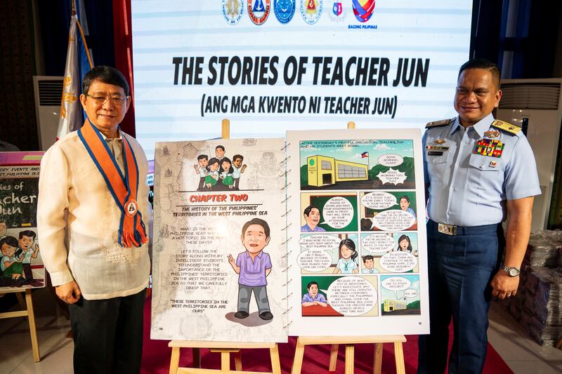 National Security Adviser Eduardo Año and Philippine Coast Guard Spokesperson for the South China Sea Jay Tarriela pose for a photo with a giant copy of the book "The Stories of Teacher Jun" during its launch at the National Library of the Philippines in Manila, Jan. 24, 2025