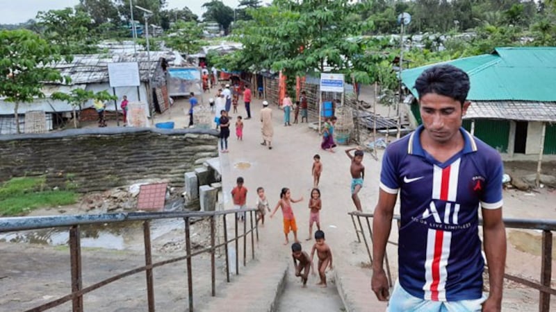 Rohingya refugee children play on a walkway after a man passes near the entrance of the Baharchara refugee camp in Teknaf, Cox's Bazar district, southeastern Bangladesh, Aug. 16, 2020.
