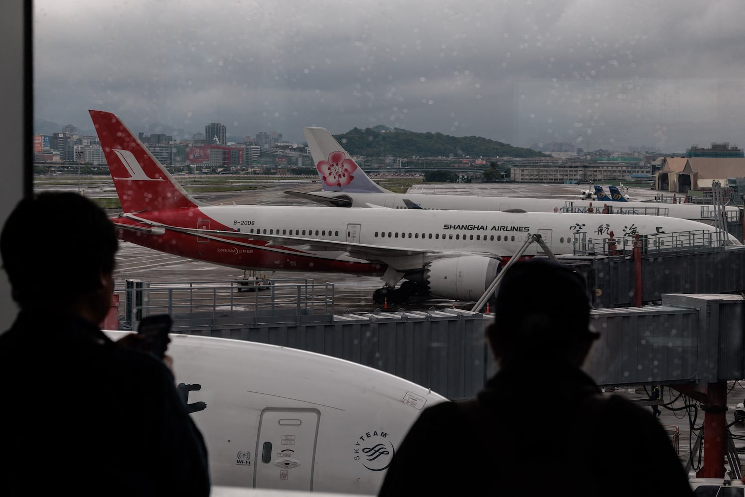 Travelers look at a Shanghai Airlines passenger plane at Songshan  Airport in Taipei on April 7, 2026.