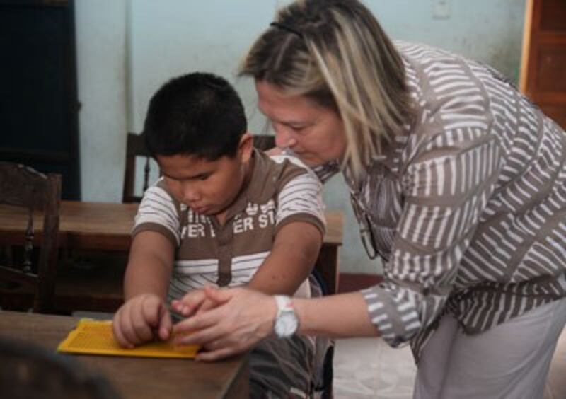 Bà Macia Selva giám đốc Quĩ Phục Vụ Cộng Đồng Toàn Cầu Global Community Sercice Fund đang giúp đỡ 1 học sinh mù ở Quảng Trị