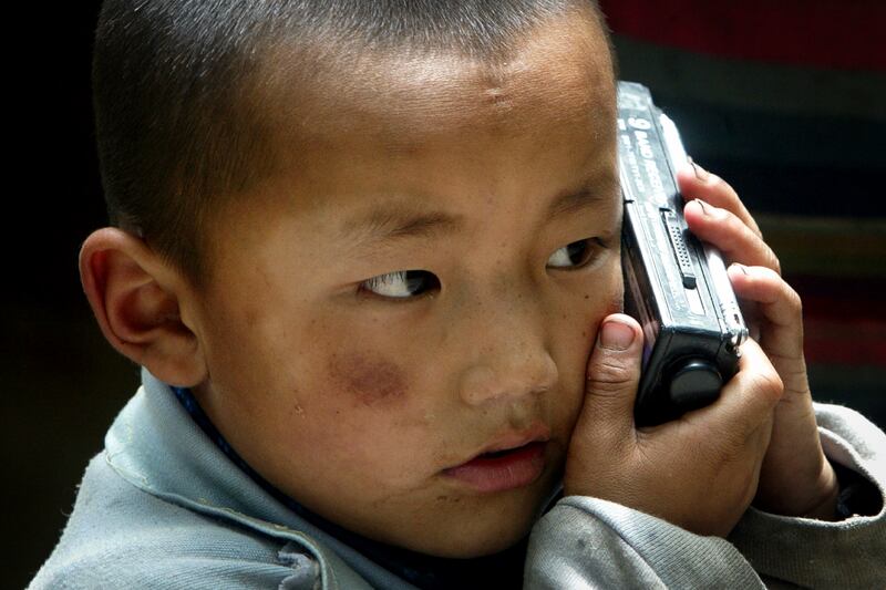 A Tibetan child listens to a radio at Sera Monastery in Lhasa, Aug. 25, 2003.