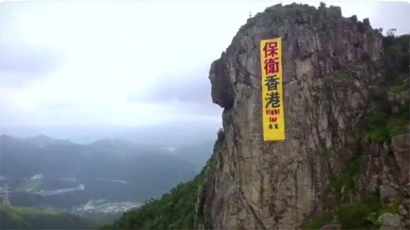 图为“保卫香港”横额挂在香港地标。(视频截图)