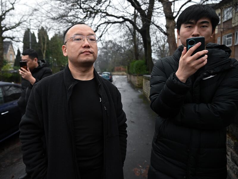 A staff member from the Chinese consulate in Manchester, center, tells a RFA reporter they can't take photos on the street outside the building, Dec. 28, 2024.