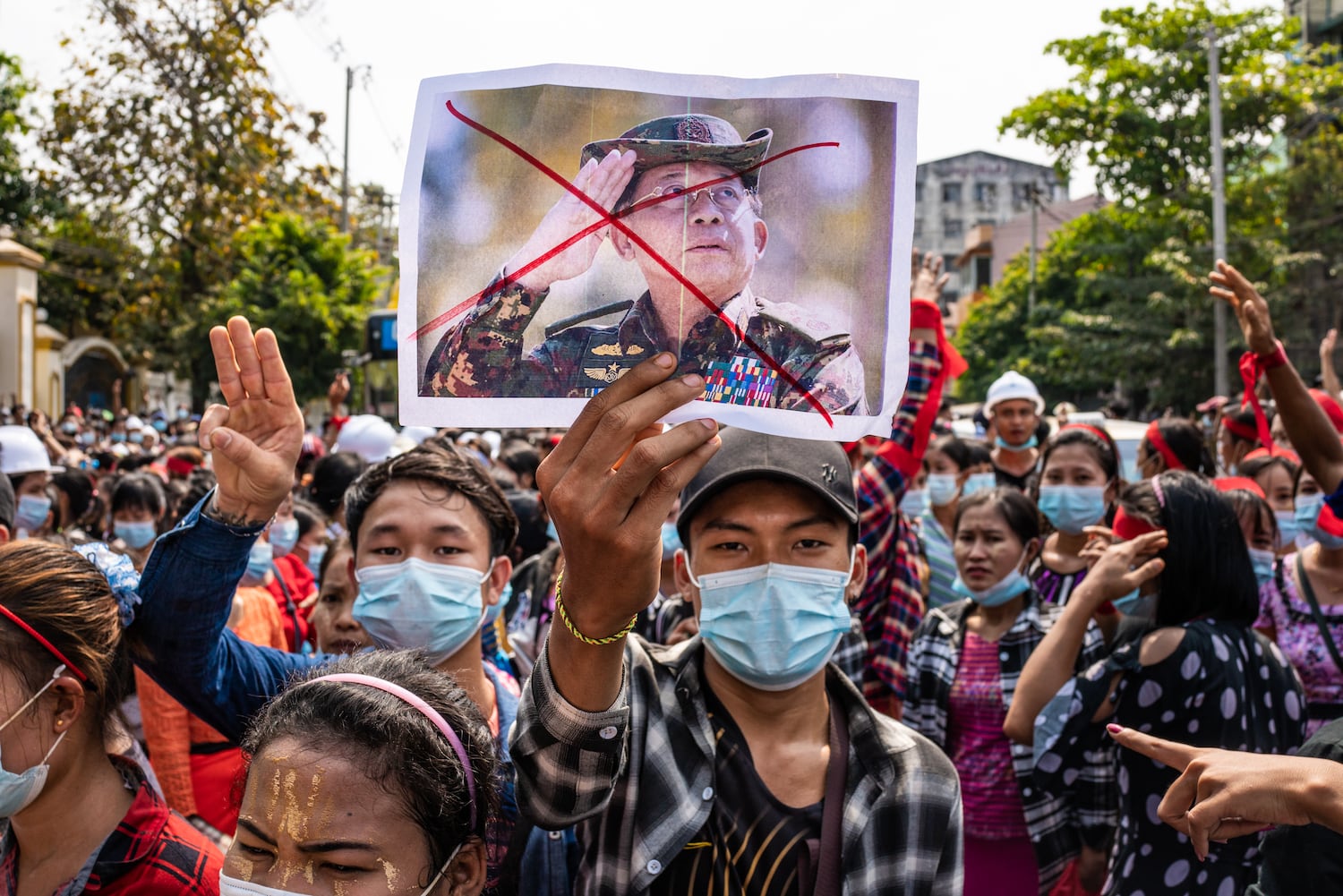\A man holds up an image of General Min Aung Hliang with a cross drawn over it during an anti-coup march on February 06, 2021 in Yangon, Myanmar.