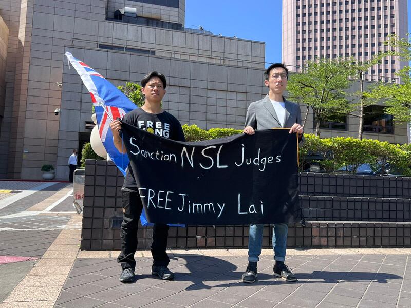 兩名在台港人帶同「龍獅旗」及寫上制裁國安法法官,釋放黎智英的橫額,到達卓慧思發表演講的會場外,希望向卓慧思遞交請願信。(淳音攝)