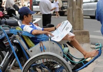 Một người chạy xích-lô theo dõi các tin tức từ kỳ họp Quốc hội qua báo chí, trong lúc ngồi chờ khách trên đường phố Sài Gòn.