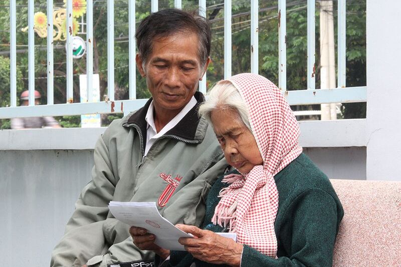 Bà Võ Thị Thương (94 tuổi) đọc quyết định đình chỉ vụ án. Bên cạnh bà là ông Nguyễn Văn Dũng 'nhỏ'.