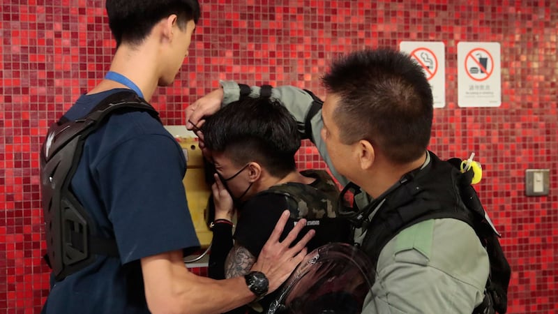 2019年9月2日,香港地铁站封锁了火车门后,警察取下抗议者的面罩。(美联社)