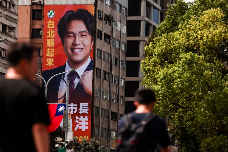 Pedestrians walk past a giant campaign billboard featuring the Democratic Progressive Party's Taipei mayoral candidate Puma Shen in Taipei on Oct. 15, 2026.