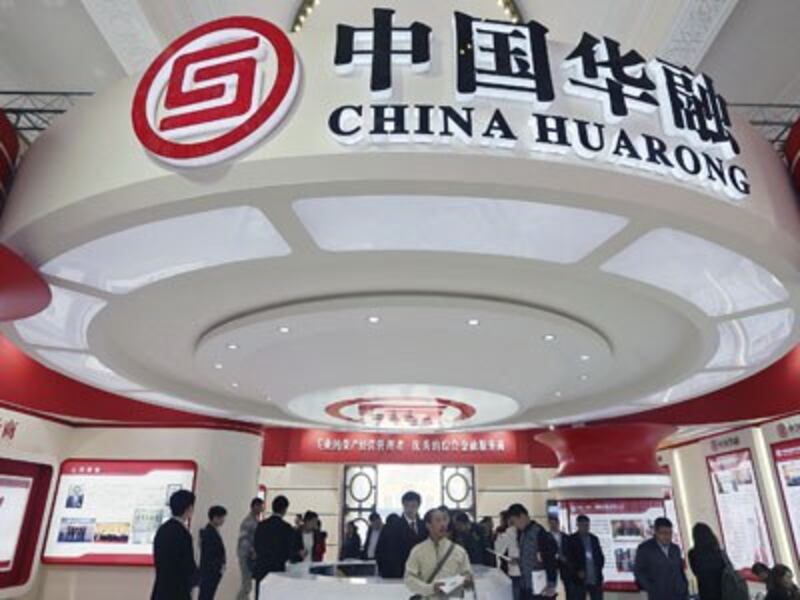 Attendees at a finance expo pass by the booth of China Huarong Asset Management Company Ltd. in Beijing, Oct. 30, 2014.