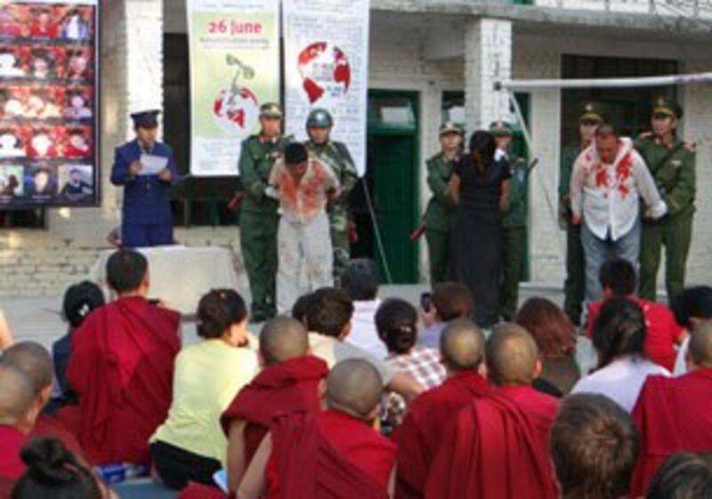 图片:达兰萨拉僧俗藏民和支持者在纪念活动上观看藏人受虐话剧(记者丹珍拍摄)