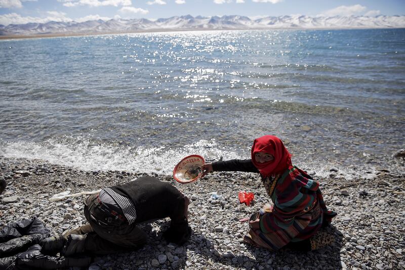 A Tibetan woman helps a man to wash his hair with water from Namtso lake in the Tibet Autonomous Region, China November 18, 2015. Located four hours' drive from Lhasa at an altitude of around 4,718m (15,479 (1).JPG
