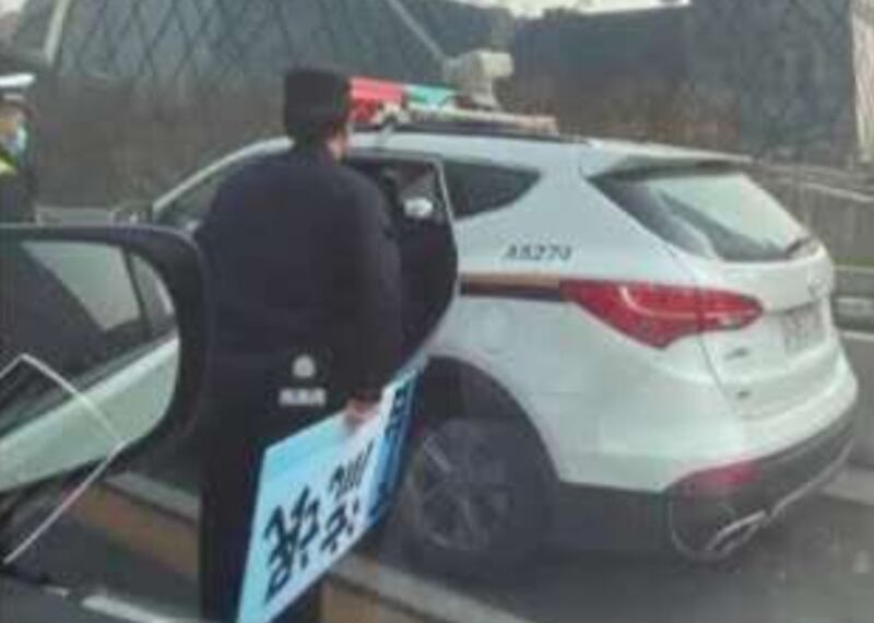 交警手持一塊沒收得來的紙牌，上面寫著「流氓下台」。（網絡圖片）