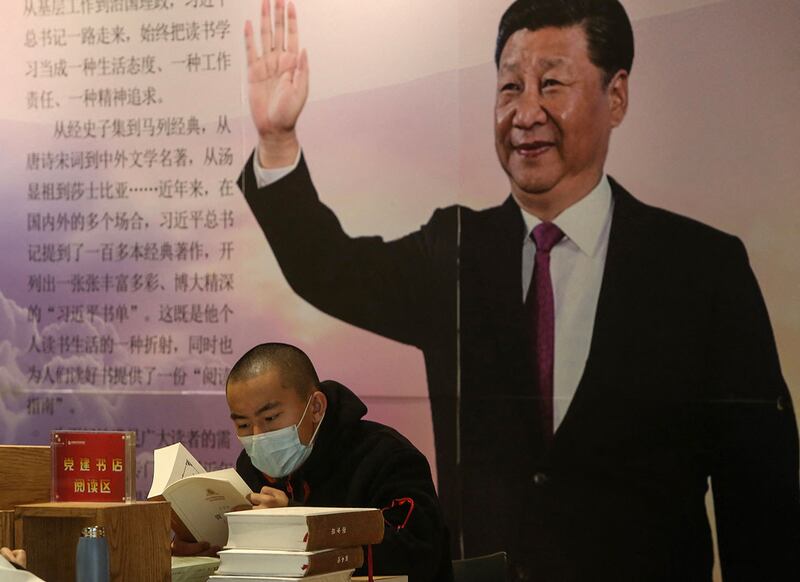 2020年4月23日，辽宁沈阳一名男子在树立习近平头像的牌子前读书。（法新社）