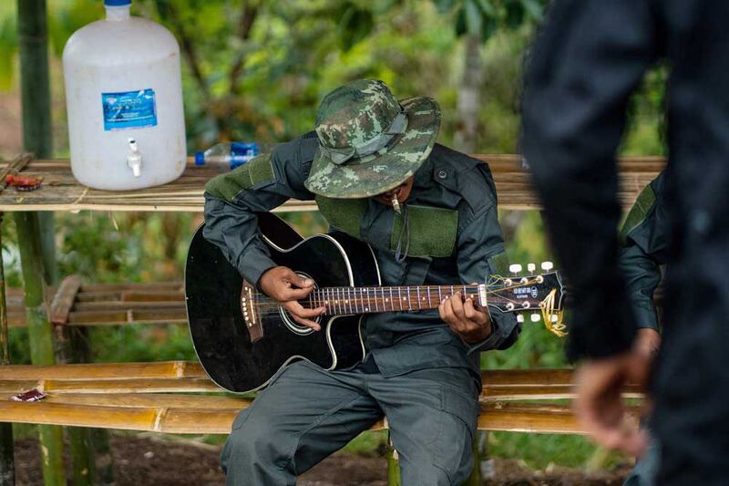 A KPDF member strums a guitar during some downtime at their camp. (AFP)