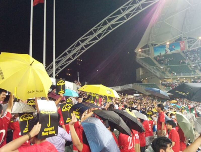 2014年10月14日，香港大球場晚上進行香港對阿根廷足球賽，於奏國歌時，香港球迷撐傘表態，並於國歌完結後唱出海闊天空。(民主黨提供)
