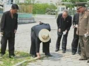 밀짚모자를 눌러쓴 김정은이 평양의 놀이공원인 만경대유희장을 찾아 직접 보도블록 사이에 난 잡초를 뽑고 있다.