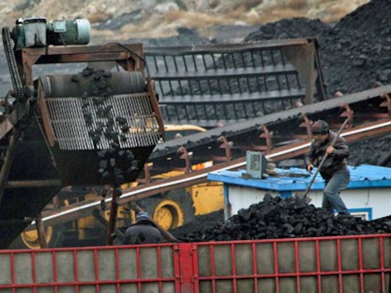 Chinese workers shovel coal as a conveyor loads it into a trailer truck at a coal mine near Ordos in northern China's Inner Mongolia Autonomous Region, Nov. 3, 2015.