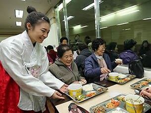 한복을 곱게 차려 입은 인제대 학생 봉사단이 지역 어르신들에게 식사를 대접하고 있다.