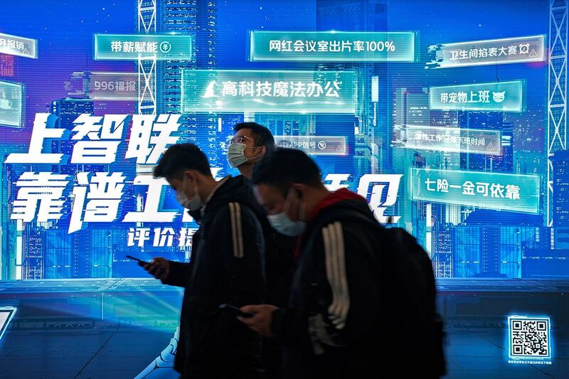 乘客在北京地铁站手机应用程序广告前浏览智能手机。(法新社)