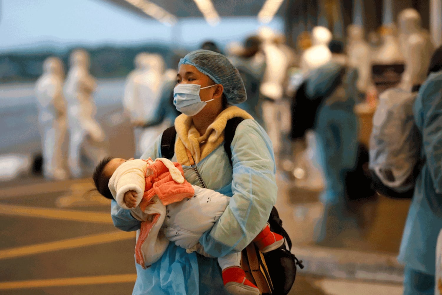 Hình minh họa. Người phụ nữ được đưa về Việt Nam từ Vũ Hán bế một em bé khi đến sân bay Vân Đồn hôm 10/2/2020