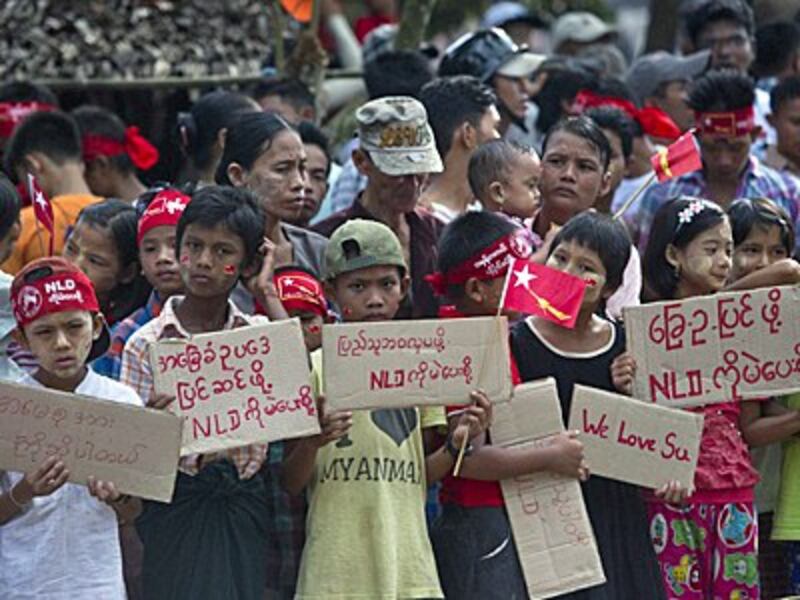 Supporters hold posters as they wait for the arrival of Aung San Suu Kyi in Kawhmu township in Yangon, Sept. 21, 2015.