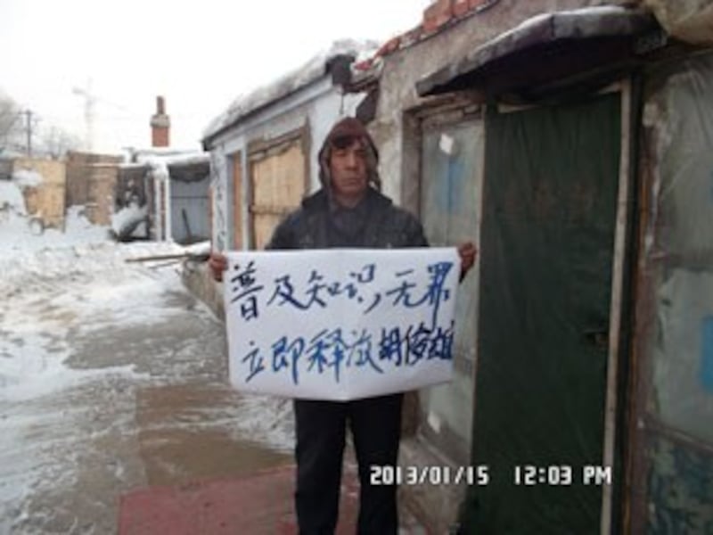 图片：一位访民展示“普及知识无罪，立即释放胡俊雄”的纸牌。（维权人士提供/记者乔龙）