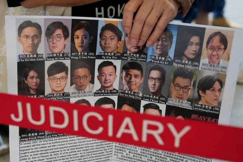 2021年7月8日，一名支持者在香港法院外举着标语牌声援47名民主被告的照片。（美联社）