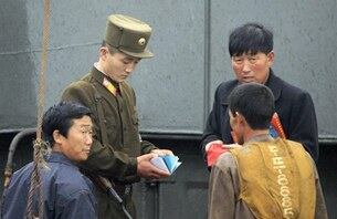북한 국경 경비대원이 압록강 선상에서 주민들을 검열하고 있다.