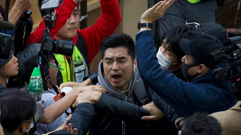 香港警察“警民关系组”一名便衣警察（中）进入遮打花园，其后被包围他的人打至头破血流。（美联社）