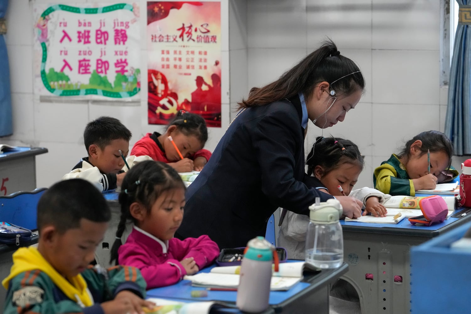 A teacher helps a student to write the alphabet in a first-grade class at the Shangri-La Key Boarding School during a media-organized tour in Dabpa county, Kardze Prefecture, Sichuan province, China, Sept. 5, 2023.