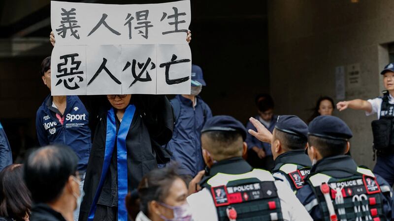 香港"四十七人案"中的吕智恒养母Elsa聆判后情绪激动，在法庭外举起"义人得生 恶人必亡"标语。 (路透社)