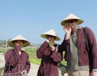 Du khách mặc chiếc áo nâu nông dân thưởng thức hương vị rau thơm Trà Quế. Courtesy Báo ảnh Vietnam