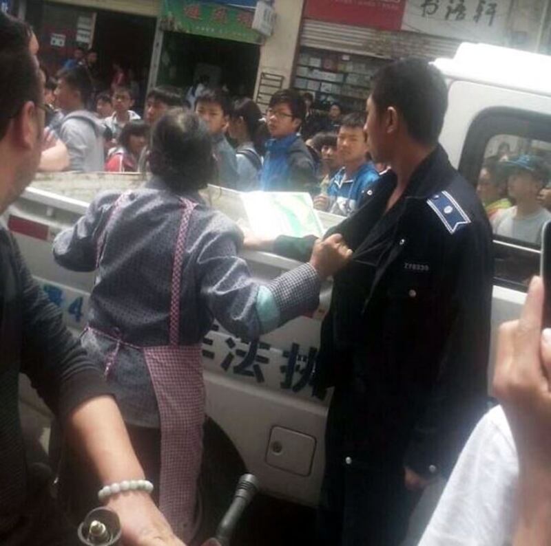 2015年4月16日，城管没收了小販老婦的香蕉，老婦不服死扯著城管的衣袖不放。(目擊者攝)