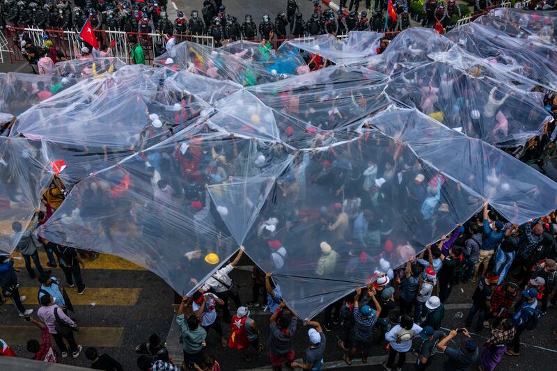 Protesters cover themselves with large plastic sheets to protect themselves from possible water cannon use against them on February 9, 2021 in Yangon, Myanmar.