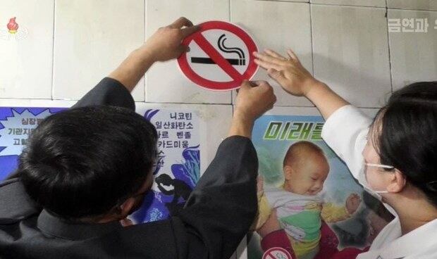 북한 금연연구보급소(금연센터) 직원들이 건물 벽면에 흡연 금지 스티커를 부착하는 모습.