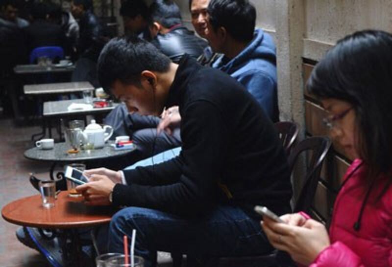 Giới trẻ VN sử dụng iPhone, iPad tại một quán cà phê vỉa hè Hà Nội năm 2013. AFP photo