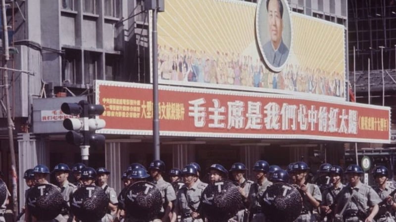 “六七暴动”期间,香港警队走过一处街头的文革标语。(维基百科)