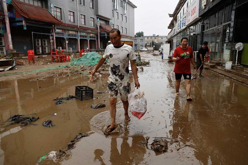 People move out items from stores after the remnants of Typhoon Doksuri brought rains and floods in Beijing, China, Wednesday, Aug. 2, 2023. Credit: Tingshu Wang/Reuters