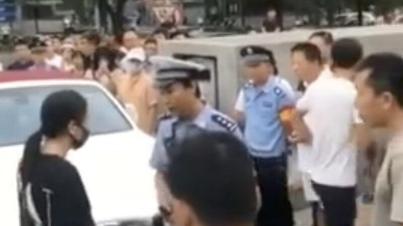 轿车司机(左)告诉警察,她拒绝挪走车辆。(微博截图)
