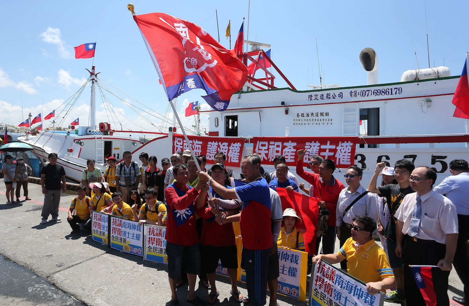 Taiwanese fishermen display flags and placards before departing to Taiping island, part of the disputed Spratly Islands chain in the South China Sea, at a fishing harbour in southern Pingtung on July 20, 2016.