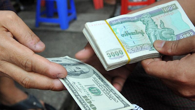 ဒေါ်လာနှင့် ကျပ်ငွေ ကိုင်ဆောင်ထားသူများကို တွေ့ရစဥ် (AFP Photo)