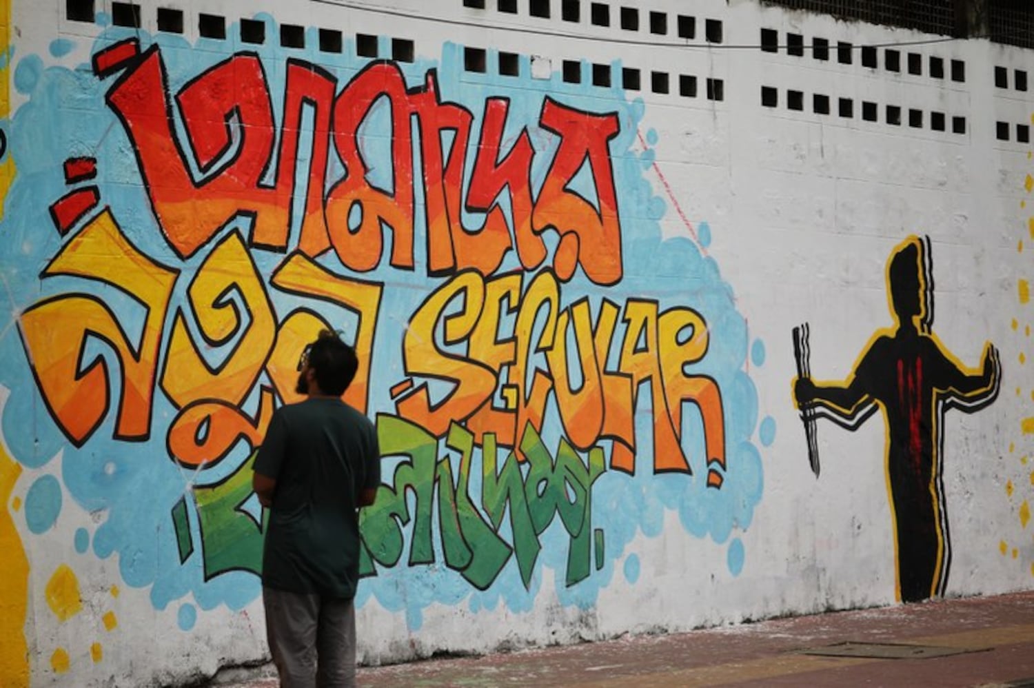 A man looks at graffiti on a wall of Dhaka University, which calls for the formation of a government that rebuilds Bangladesh, Aug. 8, 2024. (Md. Hasan/BenarNews)