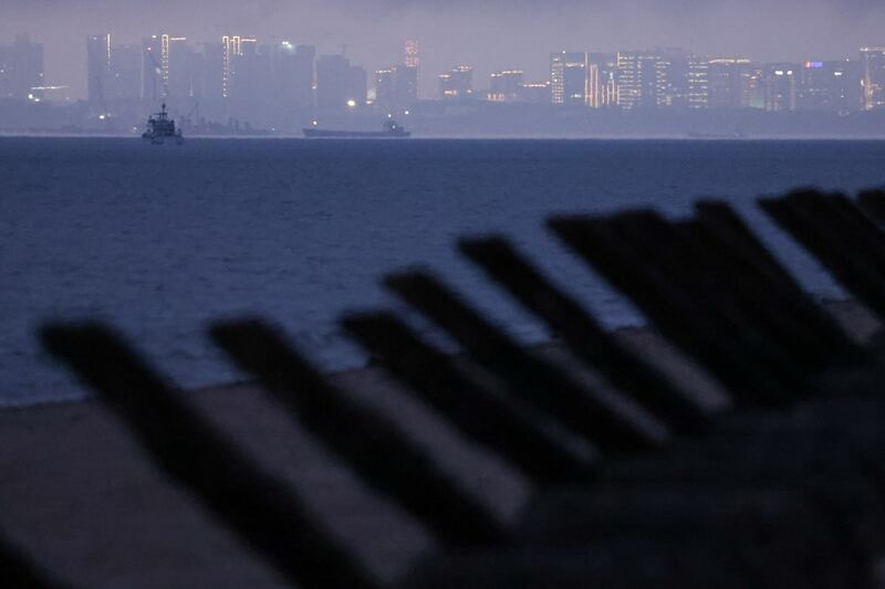 2024年2月20日,台湾金门海滩上所见的防登陆路障,背景为厦门城市天际线。(路透社)