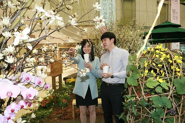 서울 AK플라자 구로본점 1층 햇빛광장에서 연인들이 실제 봄꽃과 나무로 연출된 '봄의 정원'에서 사진 촬영을 하고 있다.