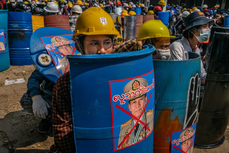Anti-coup protesters sit behind makeshift shields featuring an image of military junta leader Min Aung Hlaing on March 2, 2021 in Yangon, Myanmar.