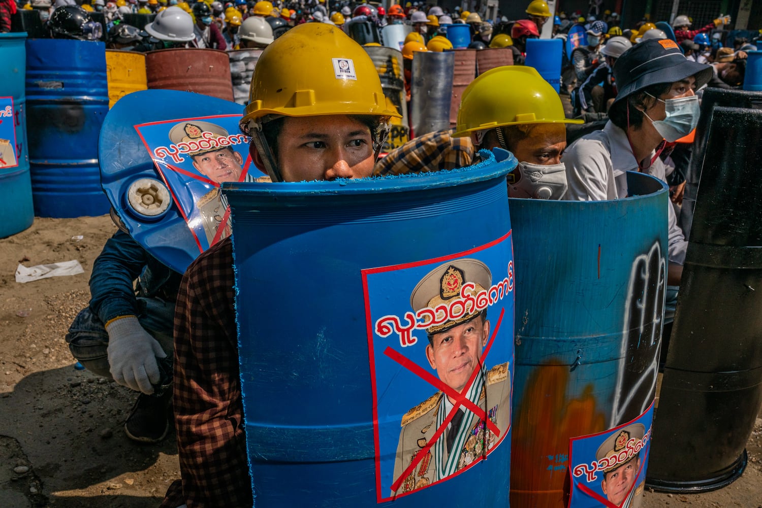 Anti-coup protesters sit behind makeshift shields featuring an image of military junta leader Min Aung Hlaing on March 2, 2021 in Yangon, Myanmar.