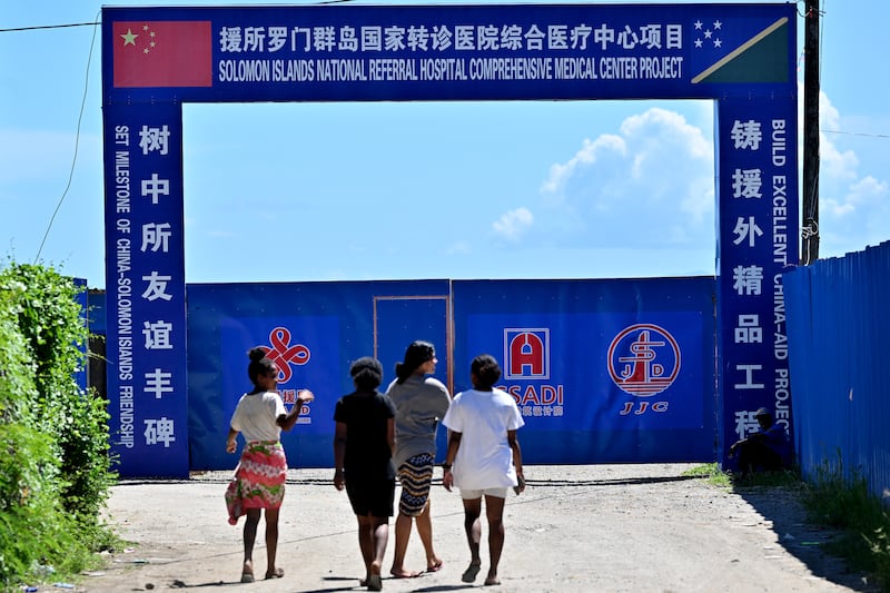Youth walk past an under-construction medical center financed by the Chinese government, in Honiara, Solomon Islands, April 21, 2024.