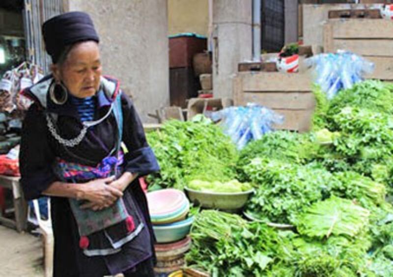 Một phụ nữ H'mong đi chợ mua rau