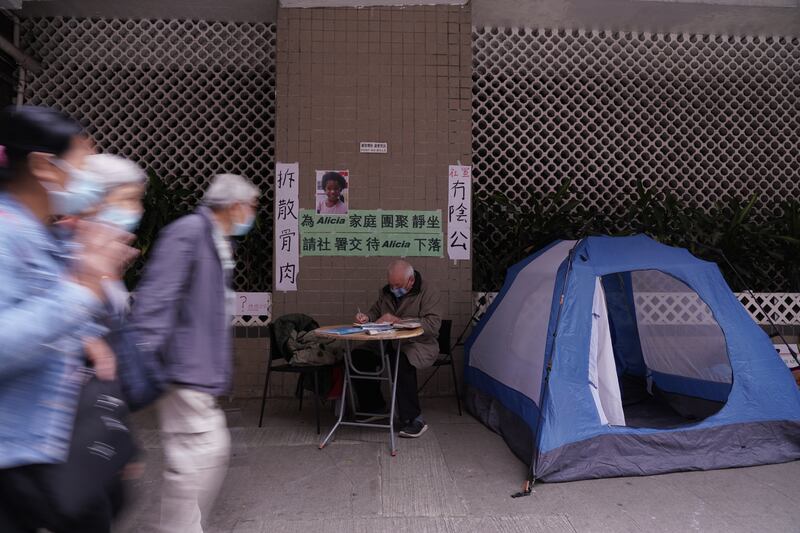 人稱「甘仔」的甘浩望神父,在社會福利署總辦事處的大廈外紮營,他擺放Alicia兒時的相片,並掛上寫有「拆散骨肉」、「冇陰公」等橫額。(石頭攝)
